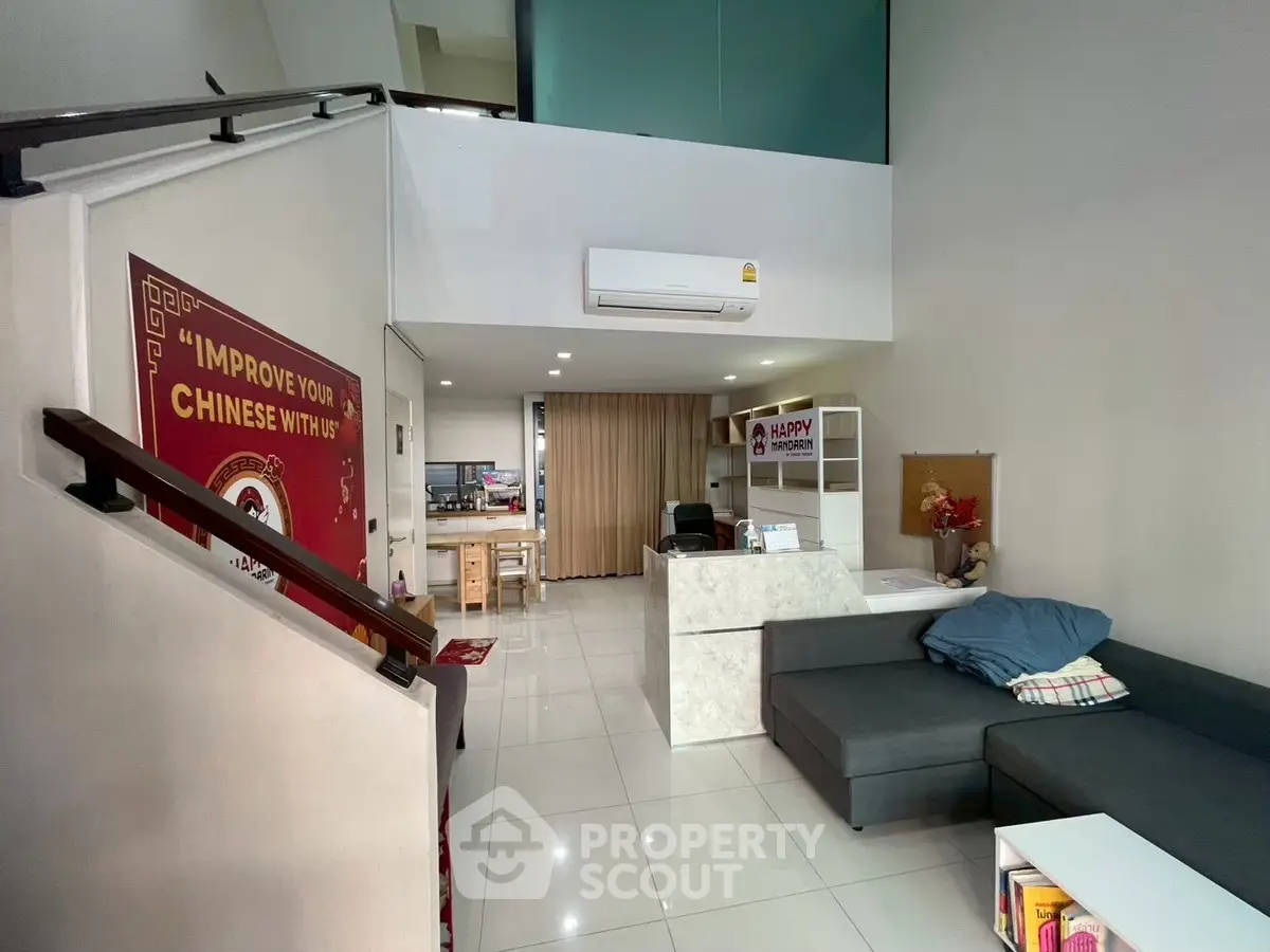 Modern duplex living room with sleek design and spacious layout, featuring a cozy sofa and stylish staircase.