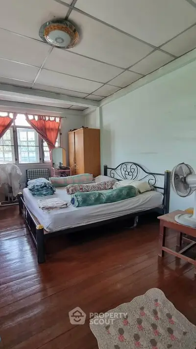 Charming bedroom with wooden floors and natural light, featuring a cozy bed and vintage decor.