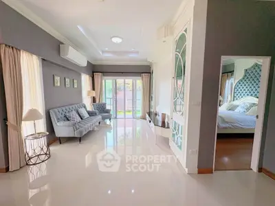 Elegant living room with stylish decor and view into a cozy bedroom, featuring modern furniture and bright natural light.