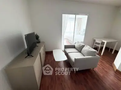 Cozy living room with modern sofa and TV, leading to a bright bedroom through sliding doors.