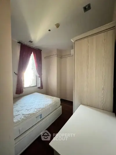 Cozy bedroom with natural light and elegant curtains, featuring a comfortable bed and stylish wardrobe.