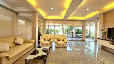 Luxurious living room with modern lighting and spacious seating area, opening to a lush garden view.