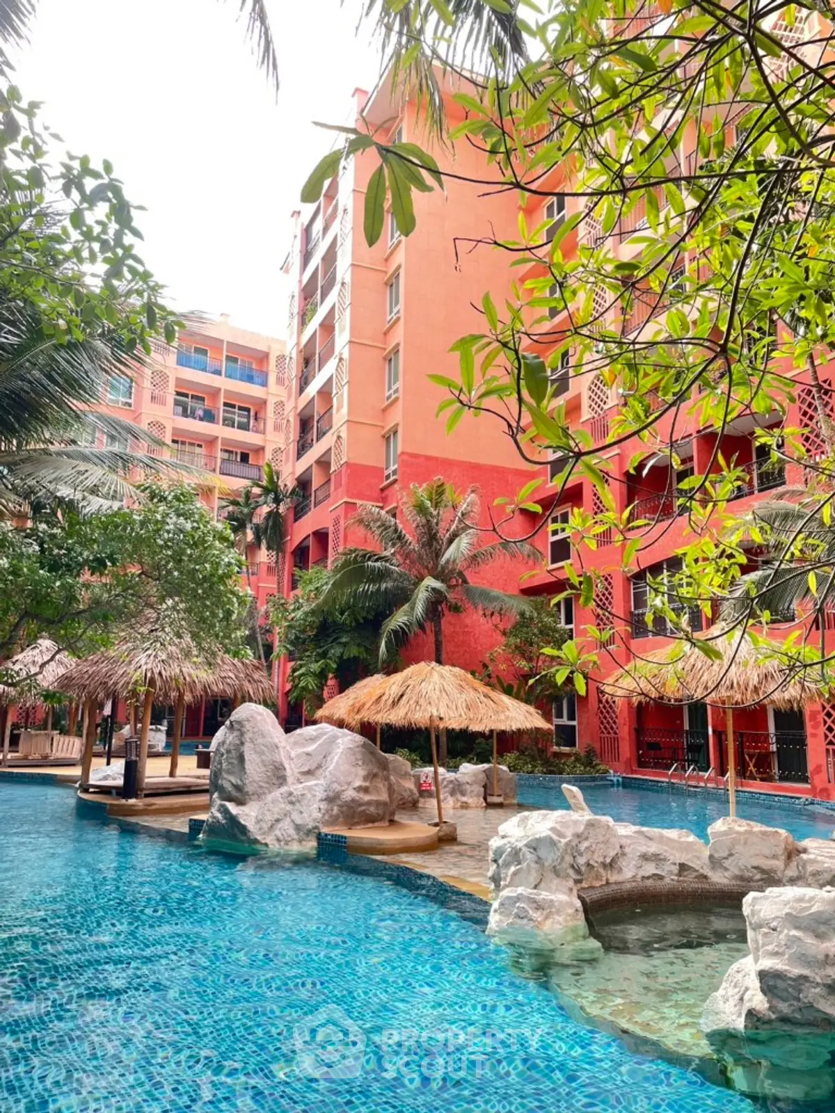 Tropical resort-style pool with lush greenery and vibrant building backdrop.