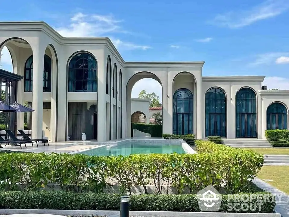 Luxurious modern villa with elegant arches and private pool, surrounded by lush greenery.