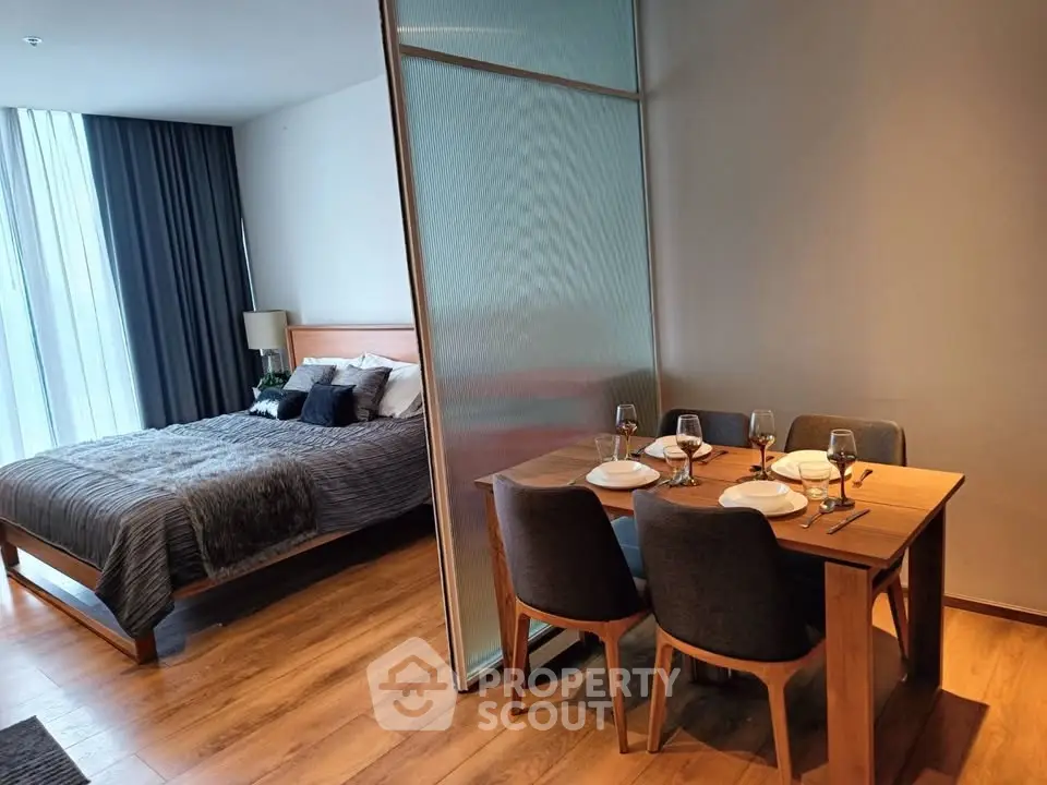 Modern studio apartment with cozy bedroom and dining area, featuring elegant wooden flooring and stylish decor.