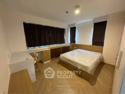 Spacious bedroom with modern furnishings and large window for natural light.