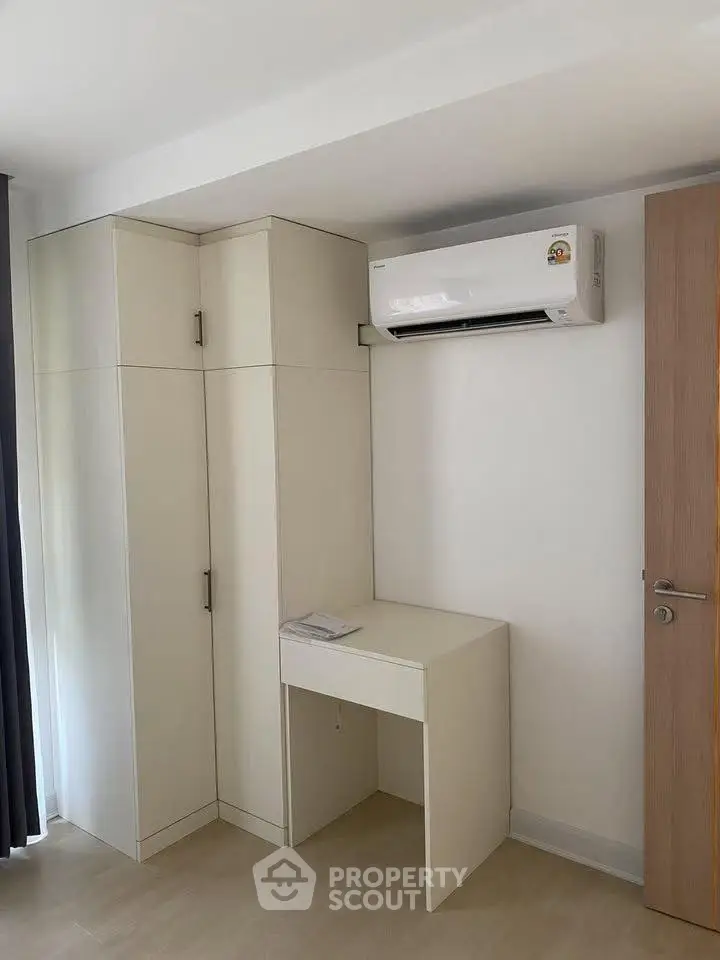 Modern minimalist bedroom with built-in wardrobe and air conditioning unit.