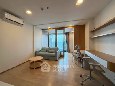Modern living room with sleek furniture and natural light, featuring a cozy sofa and stylish workspace.