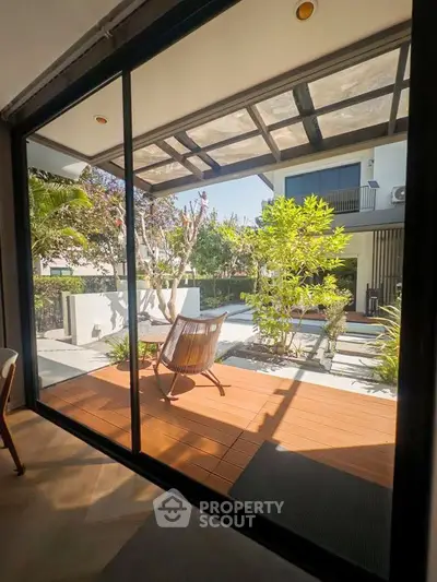 Modern patio with wooden deck and garden view through glass doors