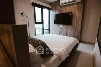 Modern bedroom with city view, featuring stylish decor and wall-mounted TV.