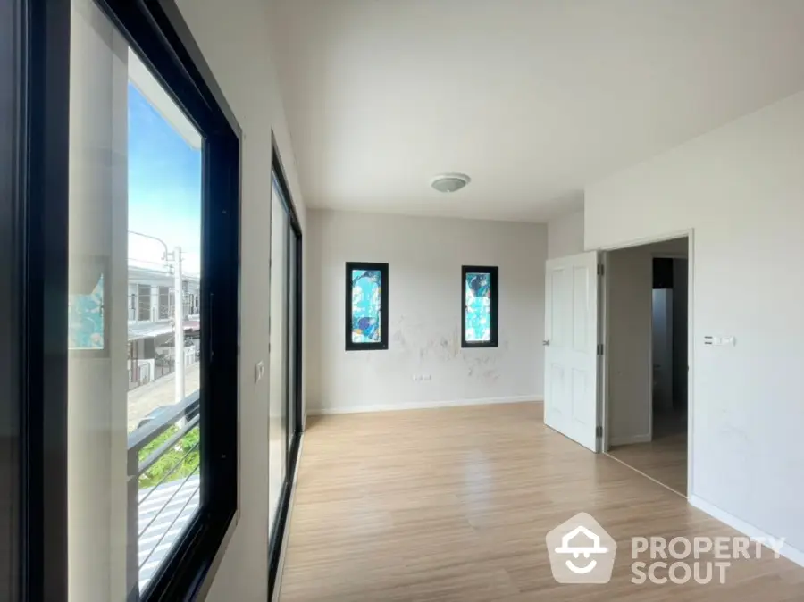 Spacious and bright living room with large windows offering ample natural light, sleek hardwood flooring, and a clean, modern design ready for personalization.