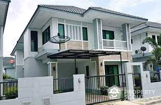 Modern two-story house with gated entrance and balcony in suburban neighborhood.