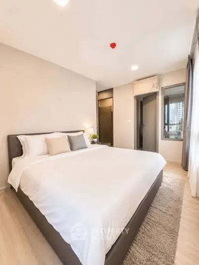 Spacious modern bedroom with large bed and natural light in a stylish apartment.