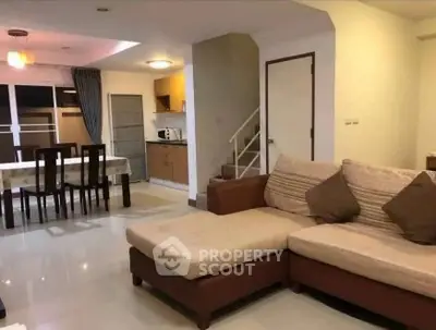 Spacious living room with modern furniture and open kitchen layout in a stylish home.