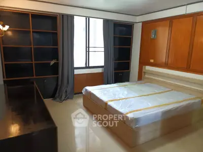 Spacious bedroom with large window and built-in wooden shelves, perfect for modern living.