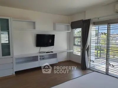 Spacious living room with modern TV setup and large windows offering scenic views.