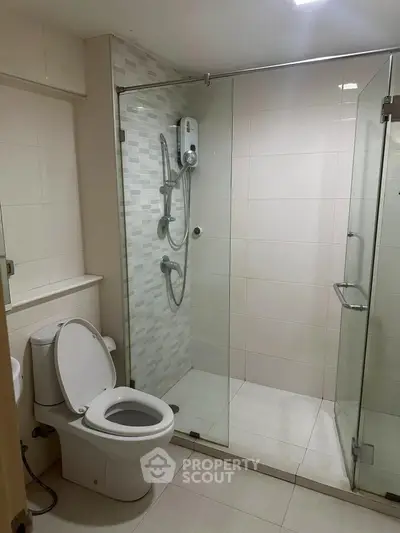 Modern bathroom with glass shower enclosure and sleek white tiles