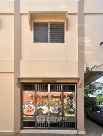 Modern building entrance with stylish metal doors and a small window above, showcasing urban architectural design.
