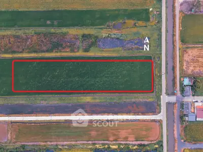 Aerial view of a rectangular plot of land with surrounding roads and greenery, ideal for development.