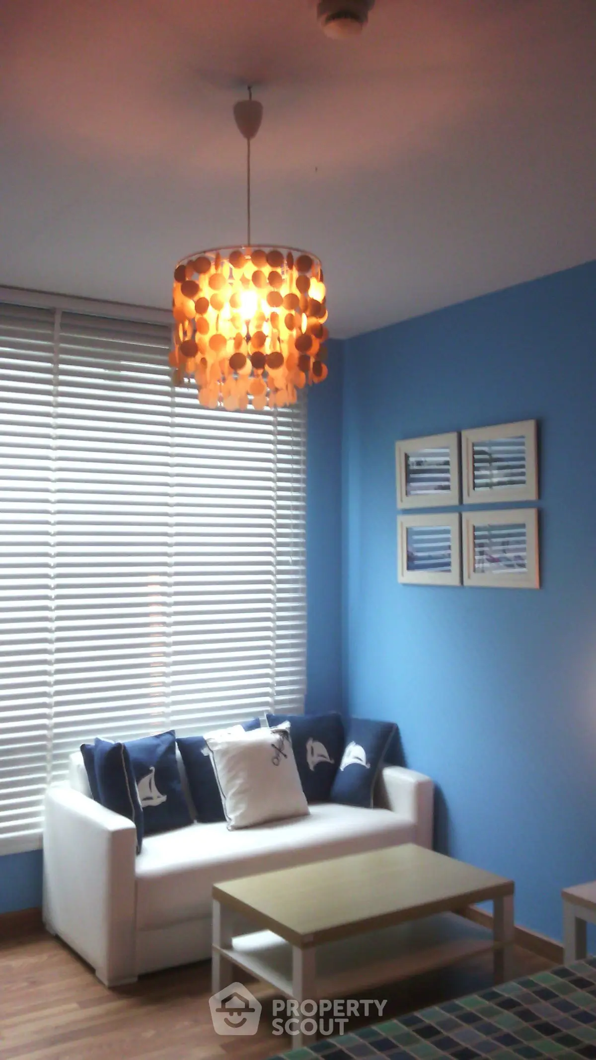 Cozy living room with blue walls and nautical decor, featuring a stylish pendant light.