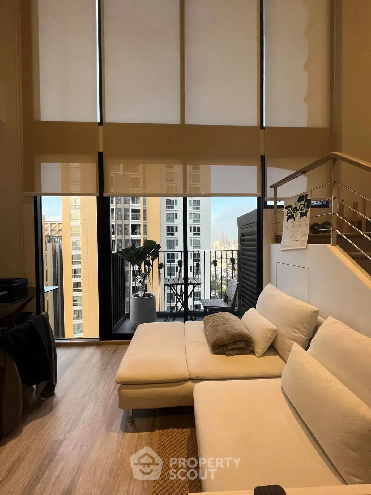 Modern living room with large windows and balcony view in high-rise apartment.