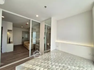 Modern bedroom with sliding glass doors and cozy living area in a stylish apartment.