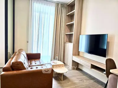 Modern living room with leather sofa, wall-mounted TV, and natural light from large window.