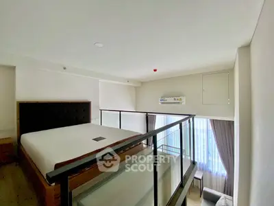 Modern loft bedroom with glass railing and natural light