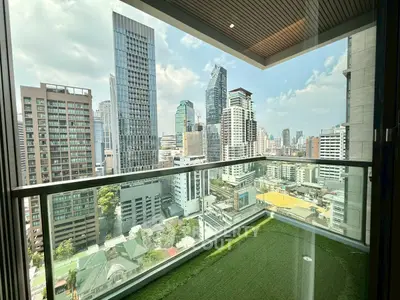 Stunning cityscape view from a modern high-rise balcony with glass railing and artificial grass flooring.