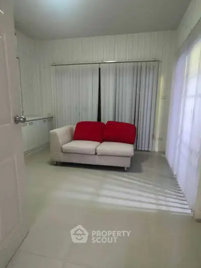 Cozy living room with white sofa and large windows with blinds.