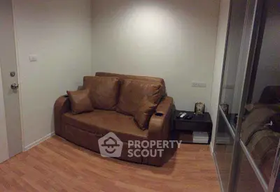 Cozy small living room with brown leather sofa and wooden flooring