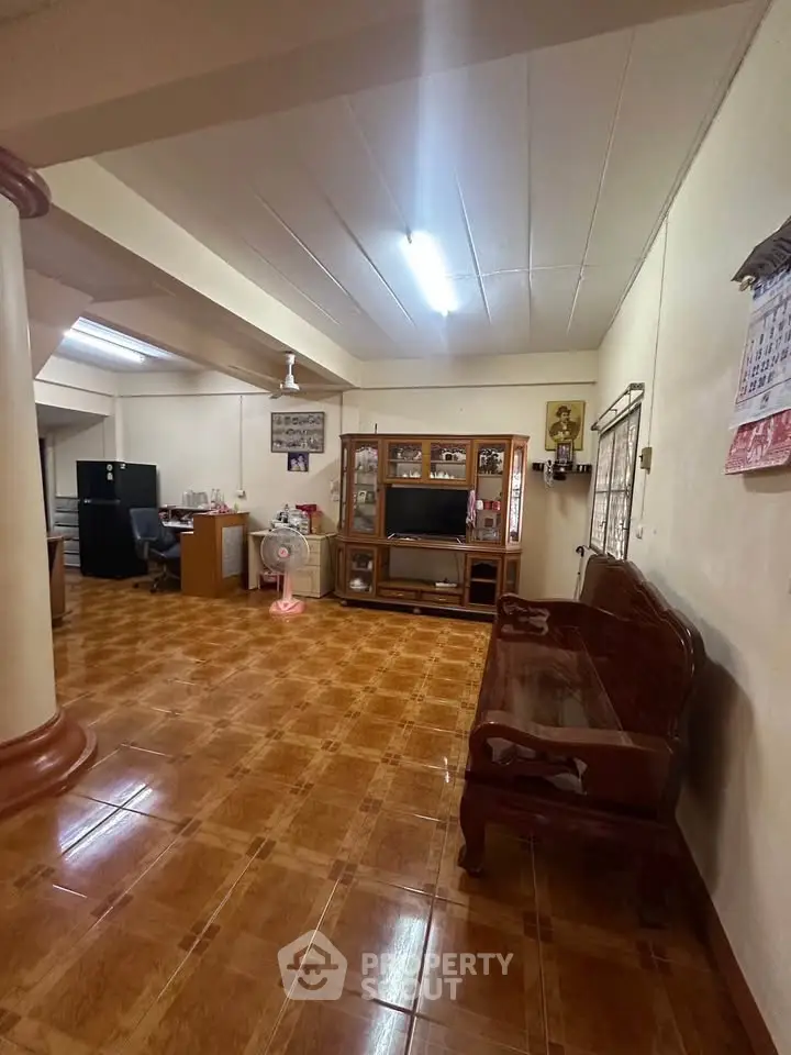 Spacious living room with wooden furniture and tiled flooring, ideal for family gatherings.