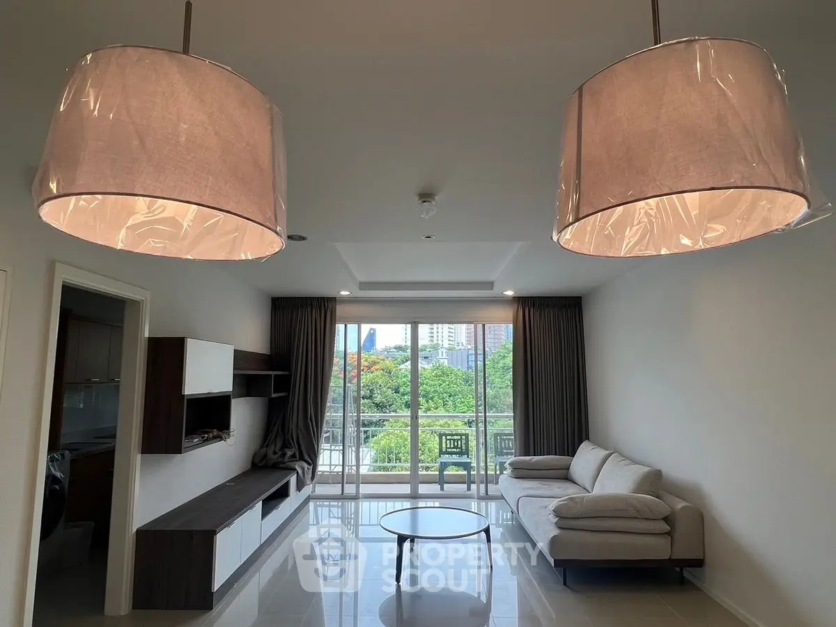 Spacious modern living room with large windows and elegant lighting fixtures.