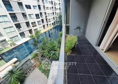 Modern apartment balcony overlooking a serene pool and garden area, perfect for relaxation.