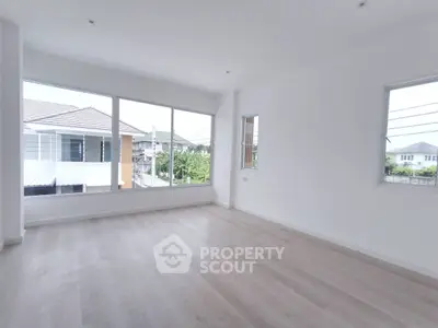 Spacious and bright room with large windows offering a serene neighborhood view.