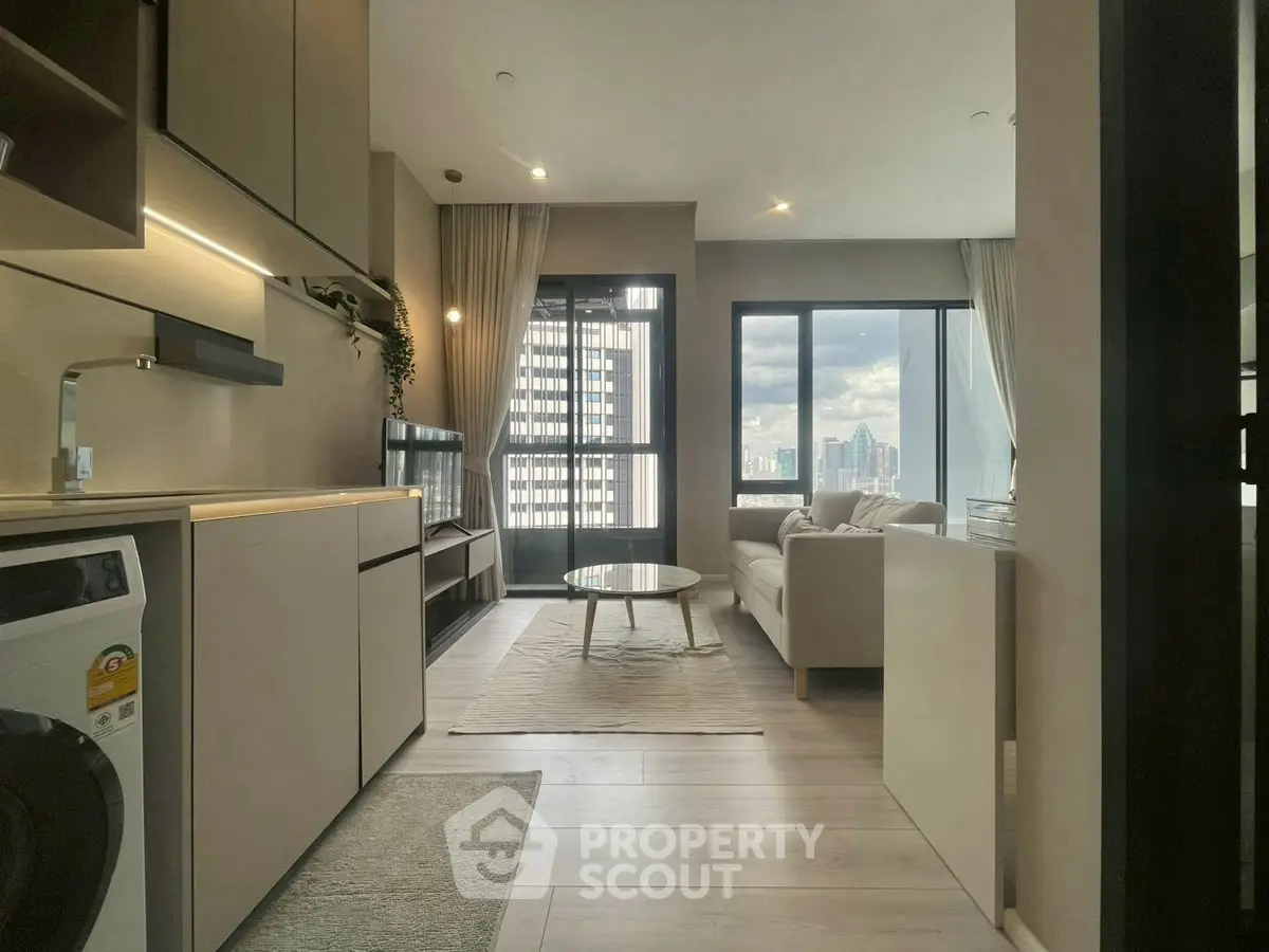 Modern living room with city view, featuring sleek furniture and integrated kitchen appliances.