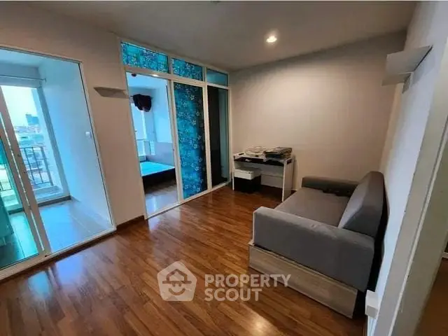 Modern living room with wooden flooring and balcony access in urban apartment