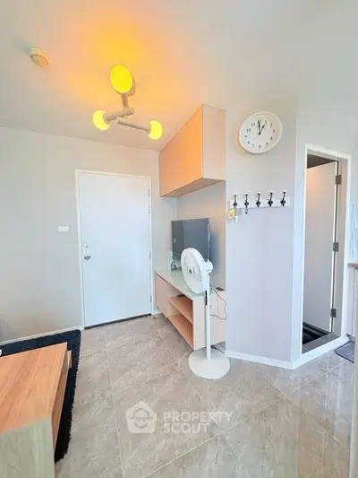 Modern living room with sleek furniture and stylish lighting, featuring a wall clock and a fan for comfort.