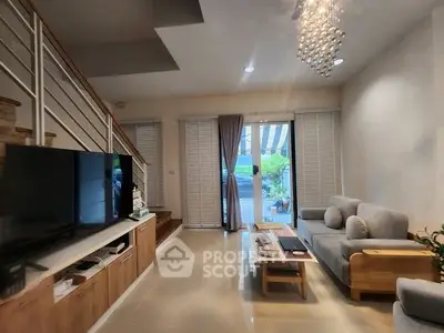 Modern living room with stylish decor and large TV, leading to a garden view.