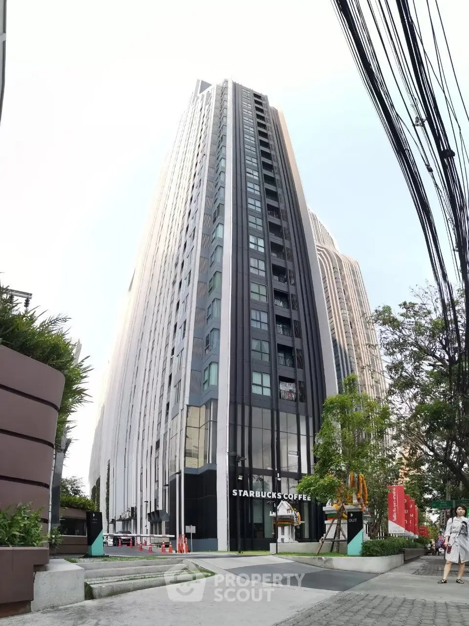 Modern high-rise building with Starbucks on ground floor, sleek architecture in urban setting.