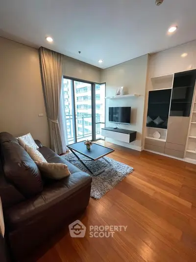 Modern living room with sleek furniture and large windows offering city views.