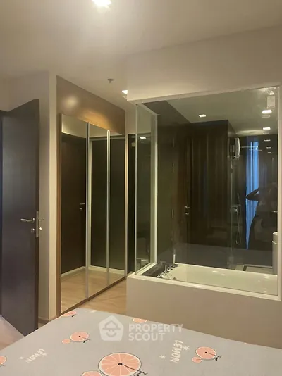 Modern bedroom with glass partition and ensuite bathroom featuring a bathtub.