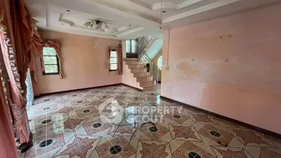 Spacious living room with elegant tile flooring and staircase, perfect for family gatherings.