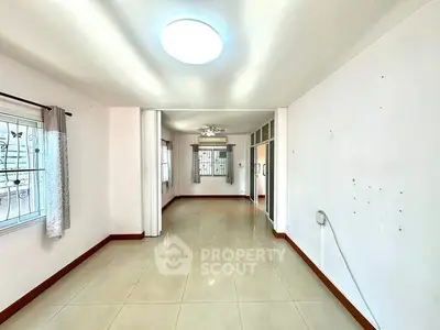 Spacious empty room with tiled flooring and large windows, perfect for customization.