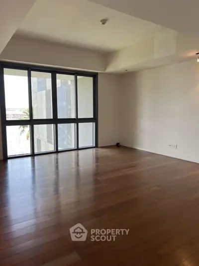 Spacious empty living room with large windows and wooden flooring