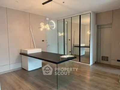 Modern study room with sleek glass desk and stylish lighting in a contemporary apartment.