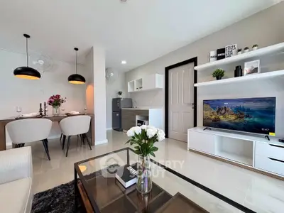 Modern living room with sleek furniture and open dining area, featuring a stylish TV setup and elegant decor.