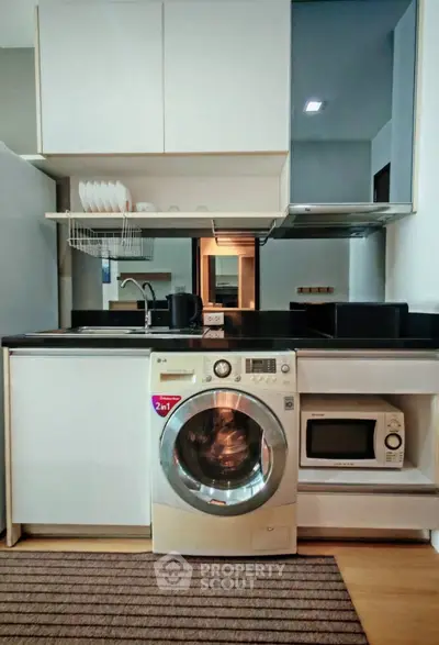 Modern kitchen with integrated washing machine and microwave, sleek cabinetry, and stylish countertop.