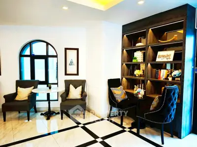 Elegant living room with stylish chairs, modern bookshelf, and natural light from arched window.