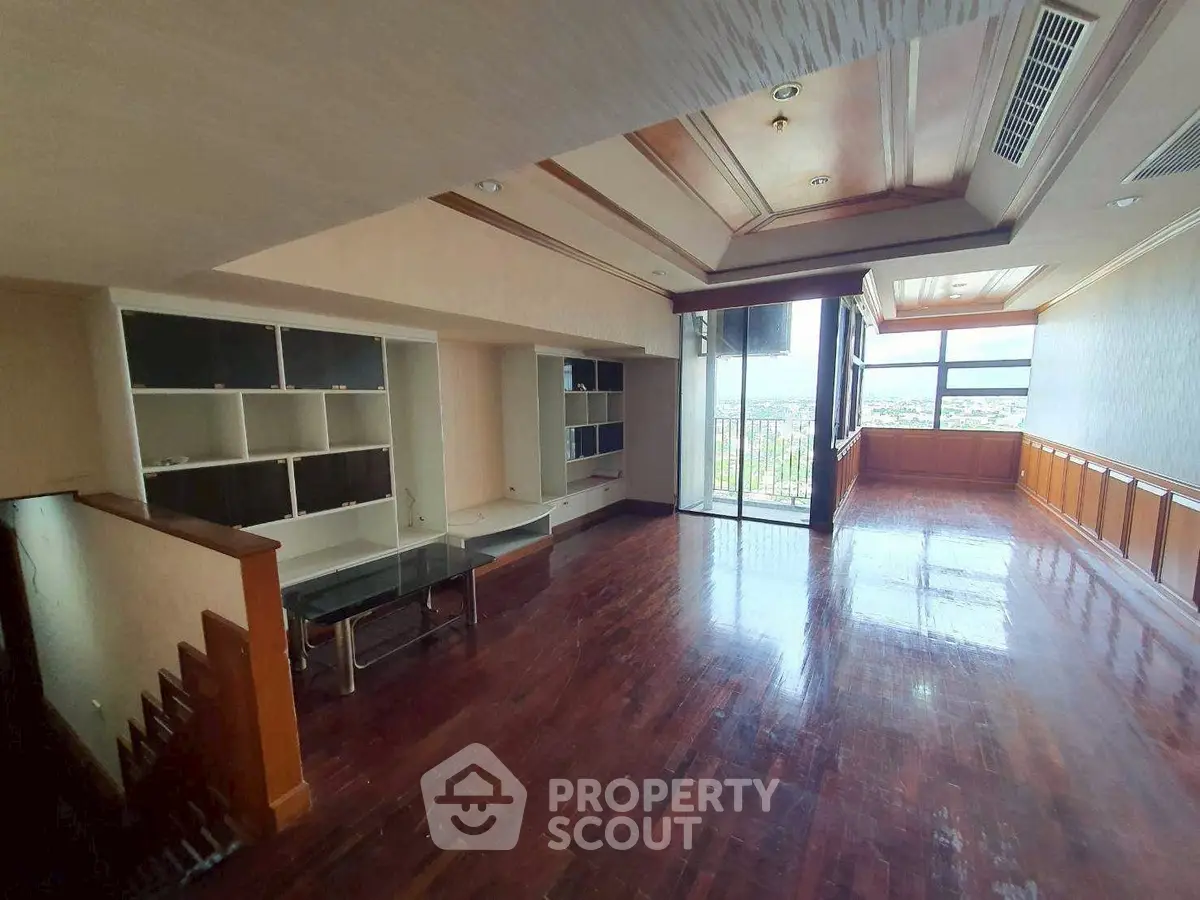 Spacious living room with hardwood floors and large windows offering a stunning view.